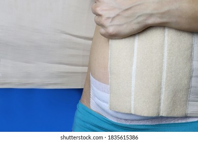 Postpartum Rehabilitation. A Woman Puts On A Corset.