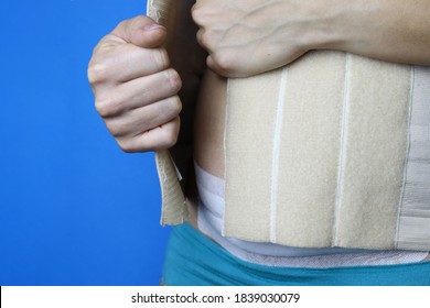 Postpartum Rehabilitation. A Woman Puts On A Corset.