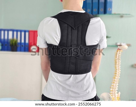 Posture correction device worn by a young individual in a clinical setting during a health assessment