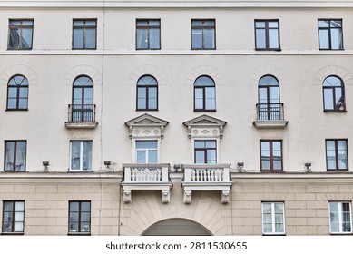 Post-war Soviet architecture concept. Close-up view of neoclassical building facade with arched windows, decorative pediments above balconies, balustrades on Independence Avenue, Minsk, Belarus