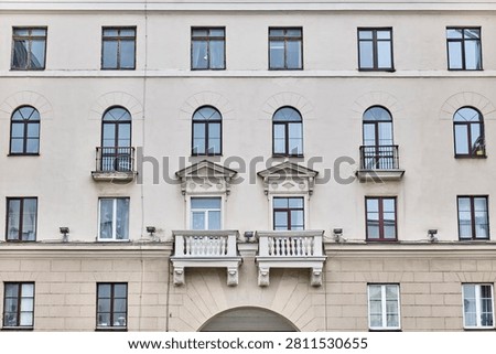 Post-war Soviet architecture concept. Close-up view of neoclassical building facade with arched windows, decorative pediments above balconies, balustrades on Independence Avenue, Minsk, Belarus