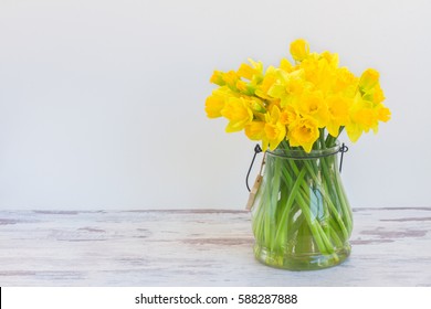 Posy of bright yellow daffodils on white wooden table with copy space
