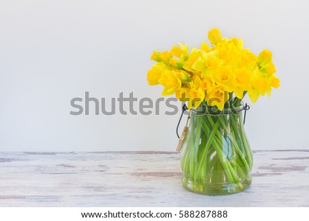 Posy of bright yellow daffodils on white wooden table with copy space
