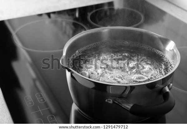 Pot\
with boiling water on electric stove, space for\
text