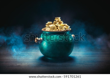 pot full of gold coins on a wooden surface and dark background / saint patricks day concept