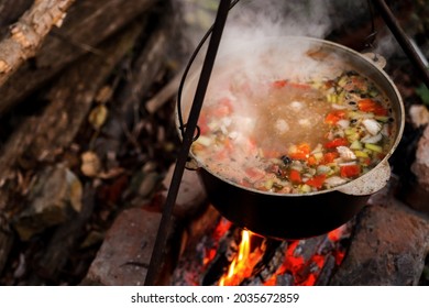 A pot of hot food in the forest, outdoor recreation at night. Hiking, travel and wilderness recreation, cooking soup over the fire. - Powered by Shutterstock