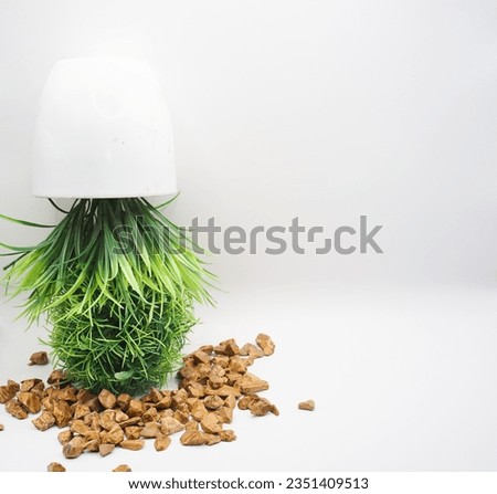 Pot with imitation flower upside down with small rocks around it