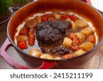 Pot roast with carrots and potatoes slow cooked in red dutch oven, on kitchen table