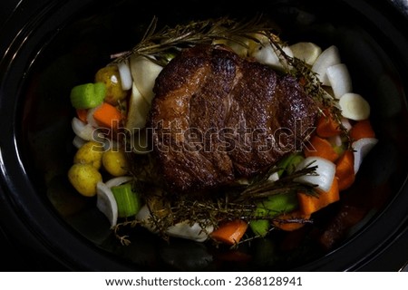 Pot roast in slow cooker with herbs ready to cook.