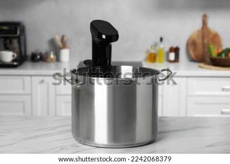 Pot with sous vide cooker on table in kitchen. Thermal immersion circulator