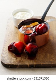Pot of stewed plums on board