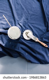 Pot Of White Paint With Brush On Top Of Blue Drop Sheet Ready To Paint, Shot At Shallow Depth Of Field With Paint Can Text Blurred