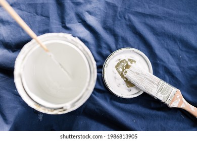 Pot Of White Paint With Brush On Top Of Blue Drop Sheet Ready To Paint, Shot At Shallow Depth Of Field With Paint Can Text Blurred