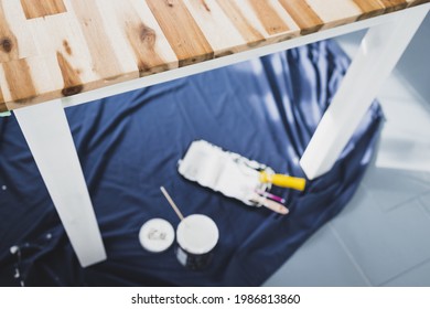 Pot Of White Paint With Paint Tray Roller And Brushes On Top Of Blue Drop Sheet Ready To Paint A Table, Shot At Shallow Depth Of Field With Paint Can Text Blurred