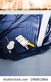 Pot Of White Paint With Paint Tray Roller And Brushes On Top Of Blue Drop Sheet Ready To Paint A Table, Shot At Shallow Depth Of Field With Paint Can Text Blurred