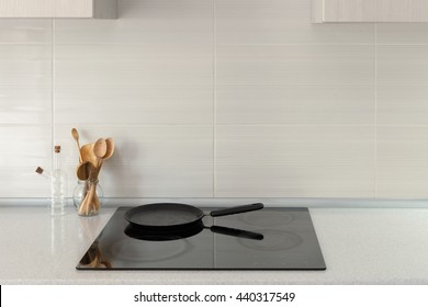 Pot and wooden spoons in modern kitchen with induction stove