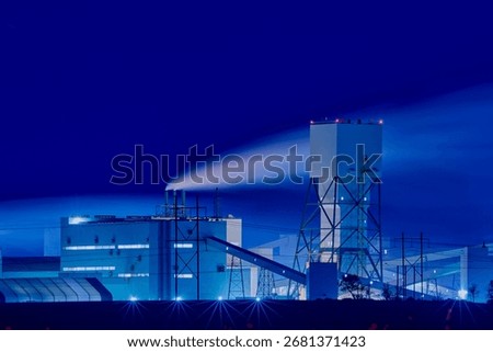 Potash mining and processing facility in Saskatchewan at night with illuminated structures and smoke under a dark sky.