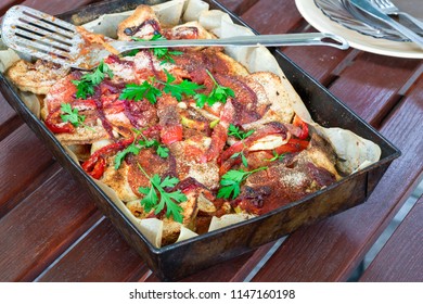 Potato, Chicken And Red Pepper Bake Garnished With Fresh Parsley In Baking Tray On Garden Table