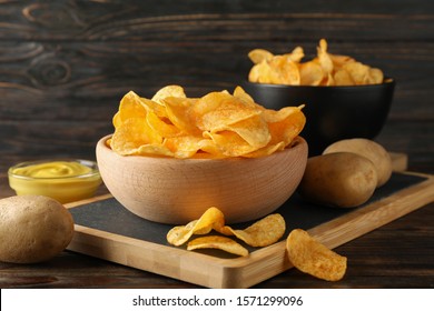 Potato chips. Beer snacks, sauce, potato on cutting board, on wooden background, space for text. Closeup