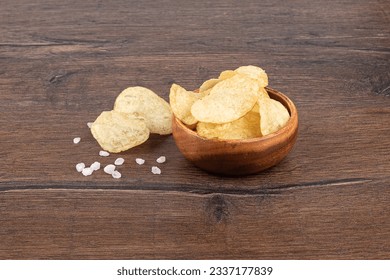 Potato chips with coarse salt are good for beer or ale snacks on a wooden table. - Powered by Shutterstock