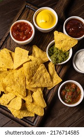 Potato Chips. Fast Food. Crispy Potato Chips Ceramic Black Bowl With Sour Cream Sauce And Onions In Wooden Stand On Old Kitchen Table Wooden Background. American Tradition. Hot BBQ. Top View.