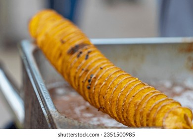 potato chips on a skewer. Spiral potatoes fried, on wooden sticks, spiral. Selling food at the market. Unhealthy fried food. Street food, a spiral fried potato on a stick.