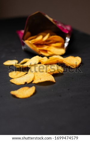 Potato crisp packet opened with crisps spilling out