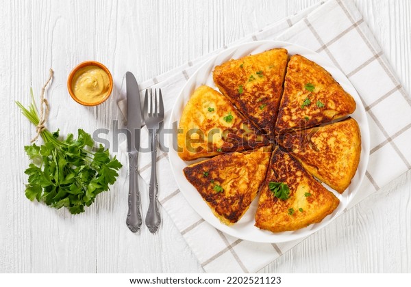 Potato Farls, Irish Potato Cakes, potato bread on\
white plate on white wooden table with cutlery, horizontal view\
from above, flat lay