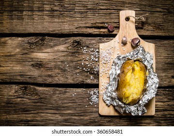 Potato Food . Baked Potatoes In Foil On A Wooden Table . Top View