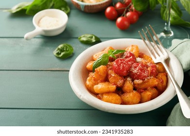 Potato gnocchi. Traditional homemade potato gnocchi with tomato sauce, basil and parmesan cheese on turquoise rustic kitchen table background. Traditional Italian food. Top view. - Powered by Shutterstock