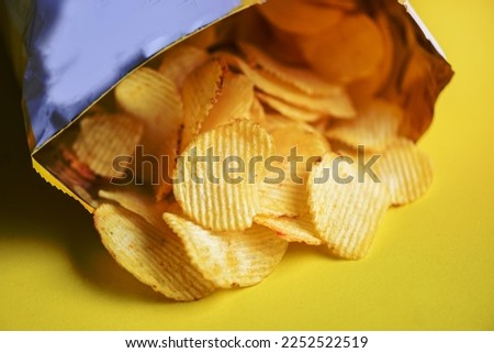 Potato hips on yellow background, Potato chips is snack in bag package wrapped in plastic ready to eat and fat food or junk food