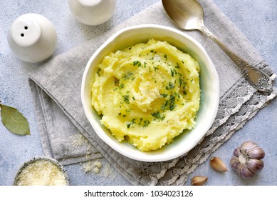 Potato mash with olive oil,parmesan cheese and greens in a bowl over light slate,stone or concrete background.Top view. - Shutterstock ID 1034023126