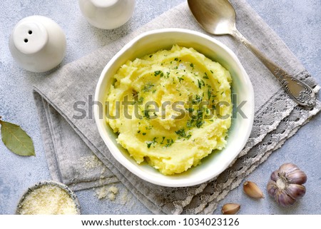 Potato mash with olive oil,parmesan cheese and greens in a bowl over light slate,stone or concrete background.Top view.