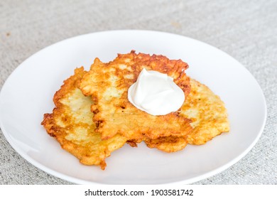 Potato pancakes, raggmunk, draniki, deruny, latkes or boxties on white plate. Polish placki ziemniaczane with sour cream.