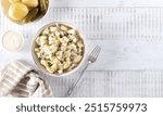 Potato salad with pickled cucumbers and onions. Top view on white background. Copy space. German, American cuisine.