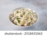 Potato salad with pickled cucumbers and onions on gray background. Copy space. German, American cuisine.