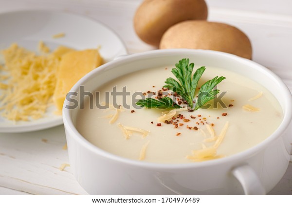 Potato\
soup with cheese and raw potatoes on the\
table.