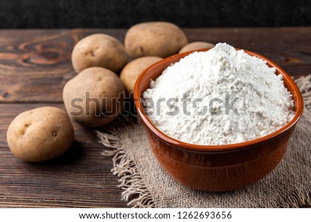 Potato starch on dark wooden background.