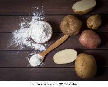 Potato starch with potatoes on a dark wooden background.