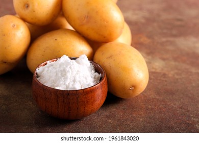 Potato starch powder in a bowl with raw potatoes