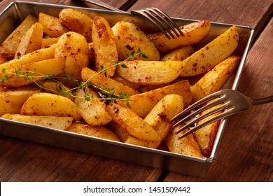 Potato wedges, oven roasted, with thyme, a close-up in a baking tray, with two forks