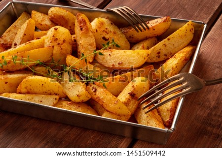 Potato wedges, oven roasted, with thyme, a close-up in a baking tray, with two forks