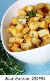 Potatoes roasted with rosemary, in stylish white bowl.  Close-up view.