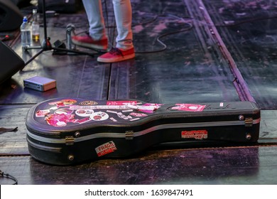 Potchefstroom, North West Province, South Africa, January 30, 2020 Out Of Focus With Grain Guitar Case Full Of Travel Stickers With Artist Feet At The Back On Stage