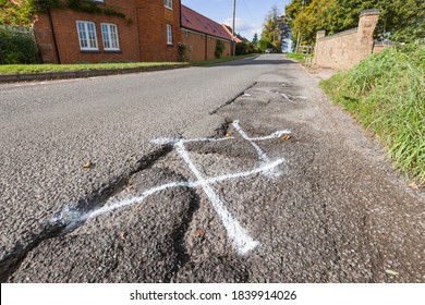 Pothole, Pot Holes In UK Country Road Marked For Highway Maintenance