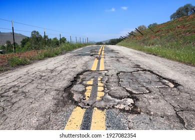 Pothole road - damaged rural road surface in California, USA.