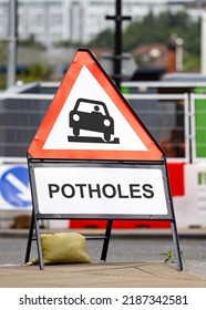 Potholes Hazard Warning Sign Dangerous Road Conditions. Red Triangle Pot Hole Message Warning Drivers Lack Of Highway Repairs And Maintenance.