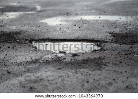 potholes in road full of rain water in UK