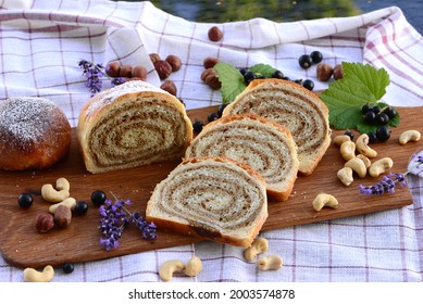 Potica, Delicious Home Baked Sweet Bread Cake With Brioche Dough And Walnut Stuffing; Bread Texture Of Sliced Sweet Walnut Roll On Wooden Board With Nuts, Black Currant, And Lavender In Background