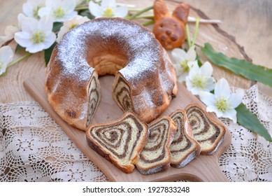 Potica, Traditional Slovenian Easter Bread Cake, Sweet Bread Roll Stuffed With Walnuts; Bread Texture Of Sliced Walnut Roll On Wooden Board With Hellebores And Easter Bread Bunny In Background